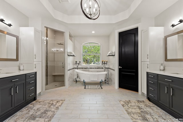 bathroom featuring plus walk in shower, a tray ceiling, a chandelier, and vanity