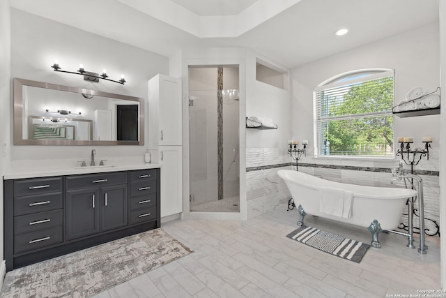 bathroom with tile walls, separate shower and tub, and vanity