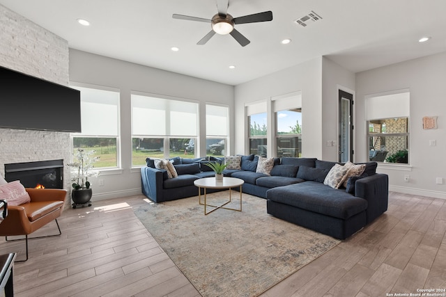 living room with light wood-type flooring, a fireplace, and ceiling fan