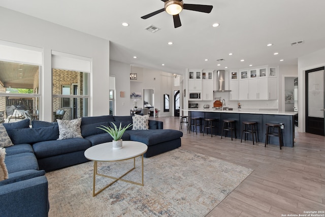 living room with light hardwood / wood-style flooring, ceiling fan, and sink