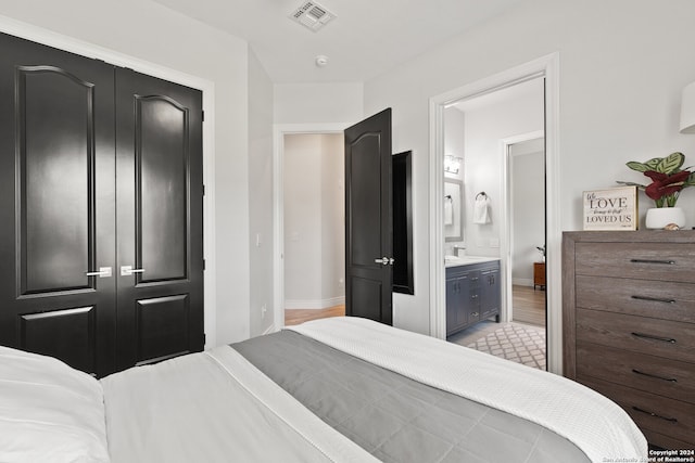 bedroom featuring light hardwood / wood-style flooring, connected bathroom, and a closet