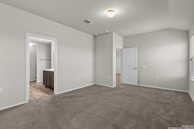 spare room featuring lofted ceiling, carpet floors, and a textured ceiling