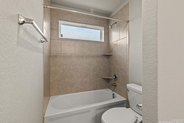 bathroom featuring tiled shower / bath combo and toilet