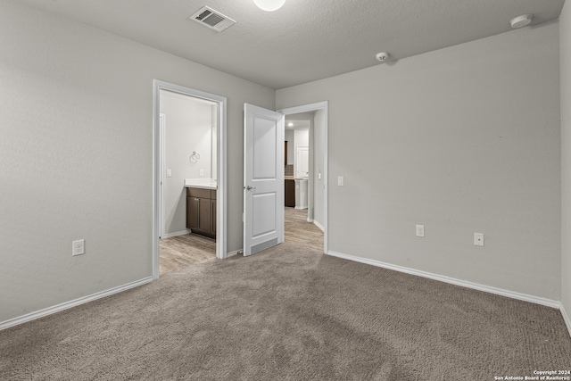 empty room with light colored carpet and a textured ceiling