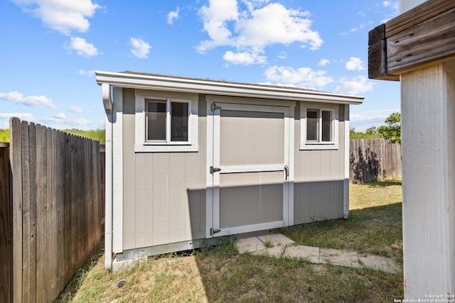 view of side of property featuring a lawn and a storage shed