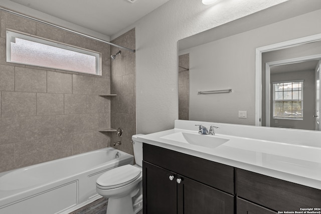 full bathroom featuring hardwood / wood-style floors, tiled shower / bath, toilet, and vanity