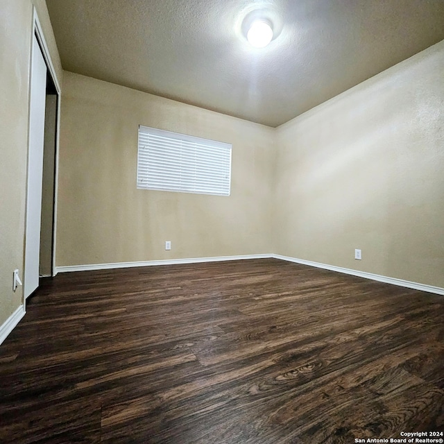 spare room featuring dark wood-type flooring and a textured ceiling