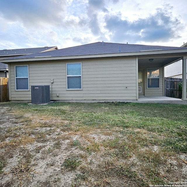 rear view of property featuring a yard and central air condition unit