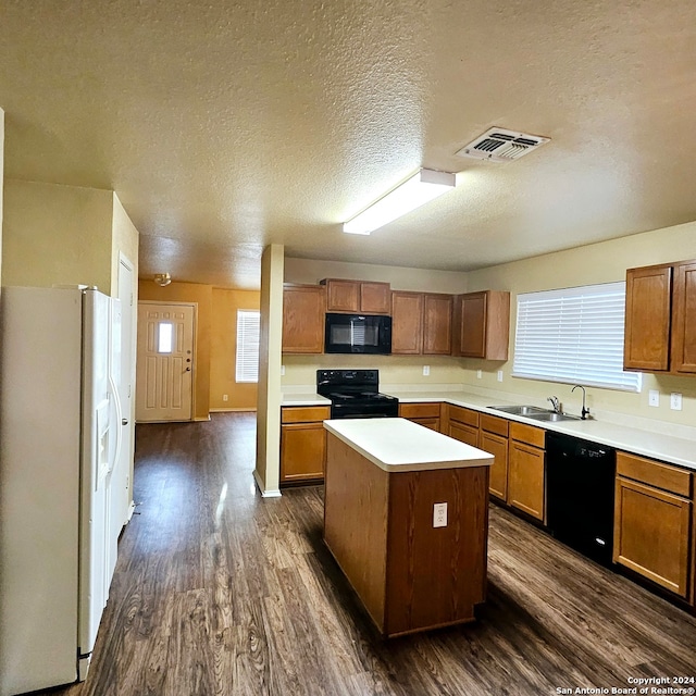 kitchen with a textured ceiling, a kitchen island, dark hardwood / wood-style flooring, black appliances, and sink