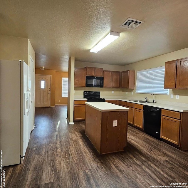 kitchen with sink, black appliances, dark hardwood / wood-style floors, a kitchen island, and a textured ceiling