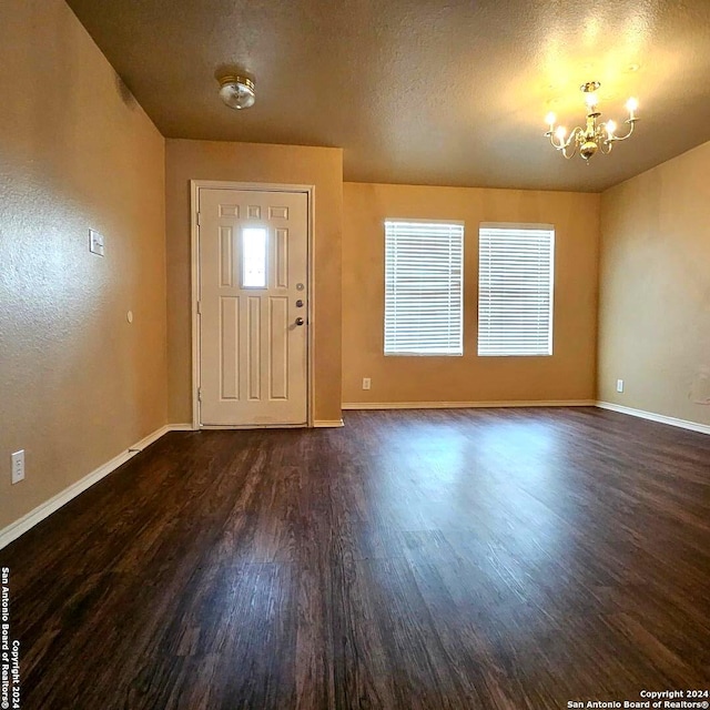 foyer featuring a wealth of natural light, a notable chandelier, dark hardwood / wood-style flooring, and a textured ceiling