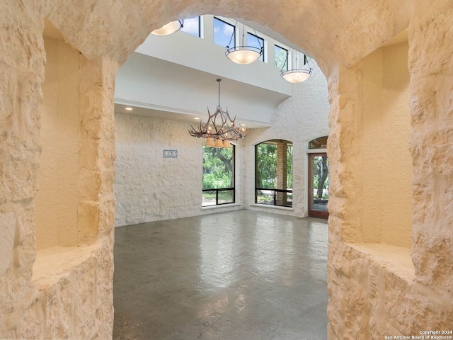 interior space with a high ceiling, finished concrete floors, and an inviting chandelier