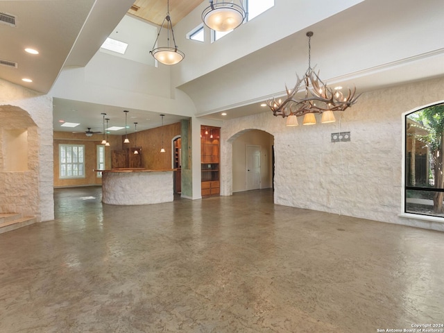 unfurnished living room with recessed lighting, arched walkways, a notable chandelier, and a high ceiling