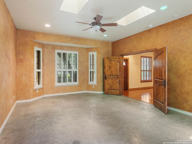 unfurnished living room with finished concrete flooring, a skylight, plenty of natural light, and recessed lighting