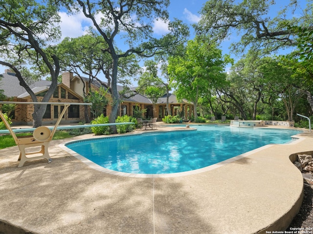 pool with a patio and a hot tub