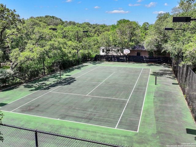 view of tennis court with community basketball court and fence
