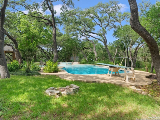 pool with a patio, a diving board, and a lawn