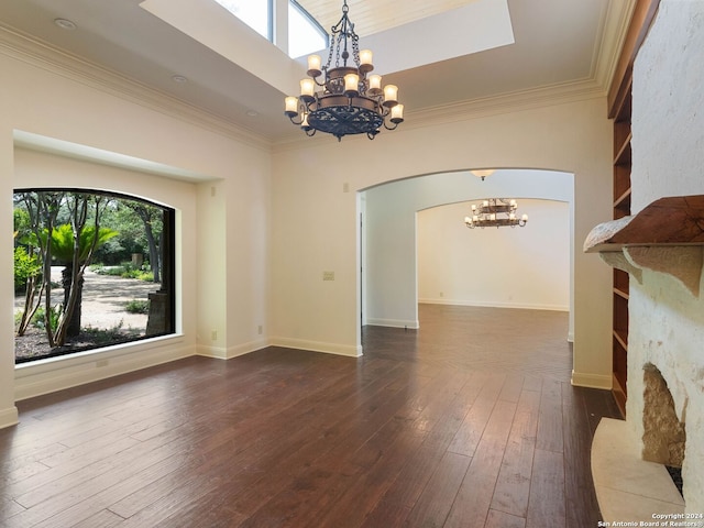 unfurnished living room featuring dark wood-type flooring, ornamental molding, arched walkways, and a notable chandelier