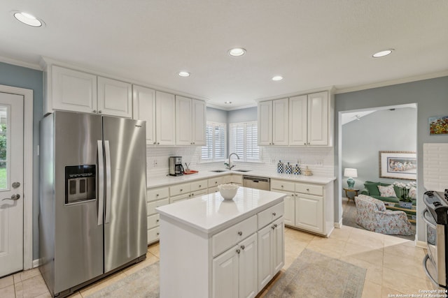 kitchen with appliances with stainless steel finishes, decorative backsplash, white cabinets, and a kitchen island