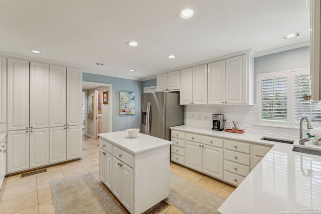 kitchen with a kitchen island, white cabinetry, stainless steel fridge with ice dispenser, decorative backsplash, and light tile patterned floors