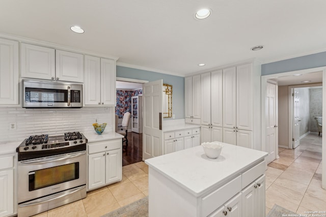 kitchen with decorative backsplash, ornamental molding, a center island, white cabinets, and appliances with stainless steel finishes