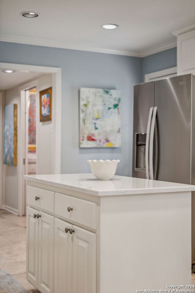 kitchen with ornamental molding, a kitchen island, white cabinets, and stainless steel fridge with ice dispenser