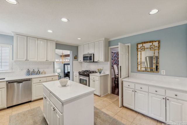 kitchen with appliances with stainless steel finishes, crown molding, and white cabinetry