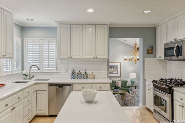 kitchen with decorative backsplash, sink, white cabinets, light tile patterned floors, and appliances with stainless steel finishes