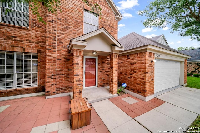 property entrance with brick siding, an attached garage, and concrete driveway