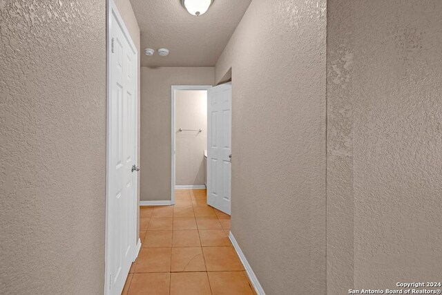 hallway featuring a textured ceiling and light tile patterned floors