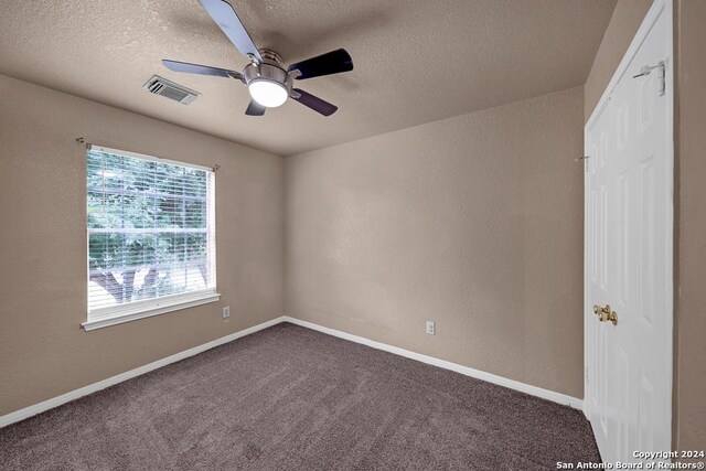 spare room featuring a textured ceiling, ceiling fan, and carpet flooring