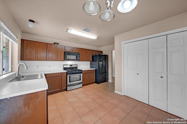 kitchen featuring black appliances, light tile patterned floors, and sink