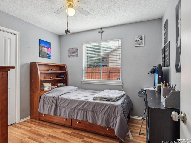 bedroom with ceiling fan, a textured ceiling, and light hardwood / wood-style flooring