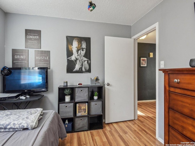 bedroom with light wood-type flooring and a textured ceiling