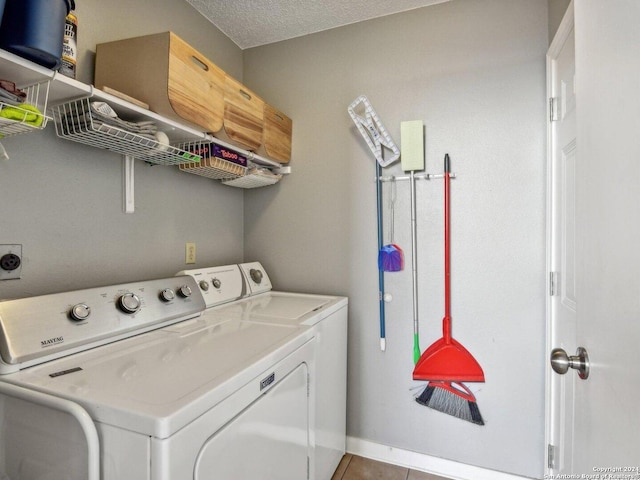 clothes washing area featuring washer and dryer, light tile patterned floors, and a textured ceiling