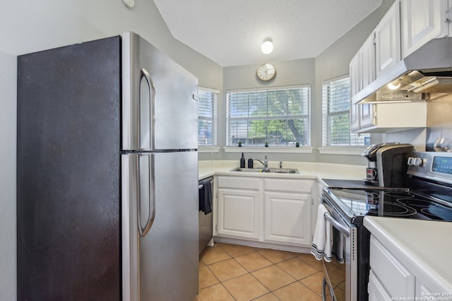 kitchen with white cabinets, appliances with stainless steel finishes, sink, light tile patterned flooring, and a textured ceiling