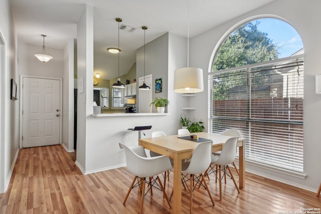 dining room with vaulted ceiling and light hardwood / wood-style flooring