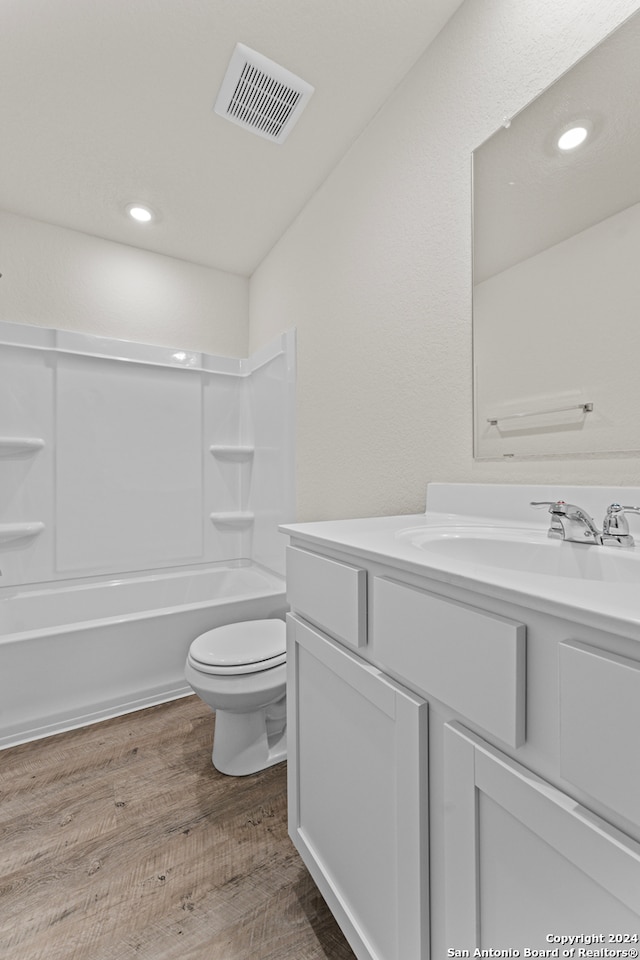 full bathroom with shower / bath combination, vanity, wood-type flooring, and toilet