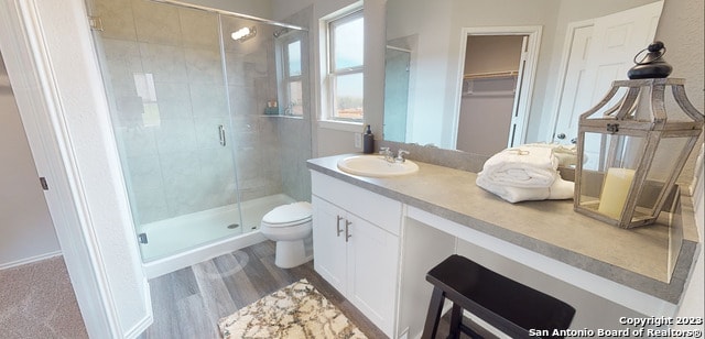 bathroom with hardwood / wood-style floors, vanity, toilet, and a shower with shower door