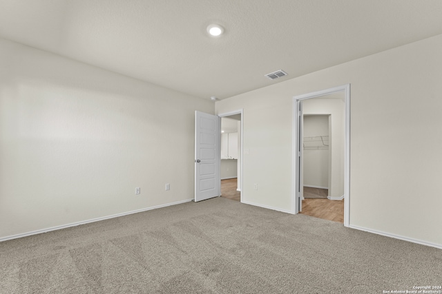 unfurnished bedroom with light carpet, a spacious closet, and a closet