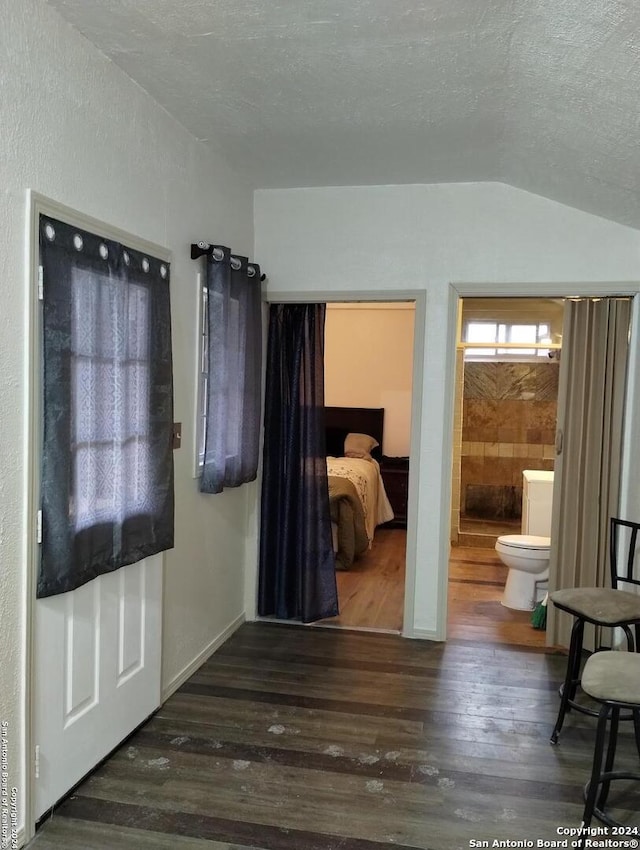 interior space featuring a textured ceiling, vaulted ceiling, and dark hardwood / wood-style floors