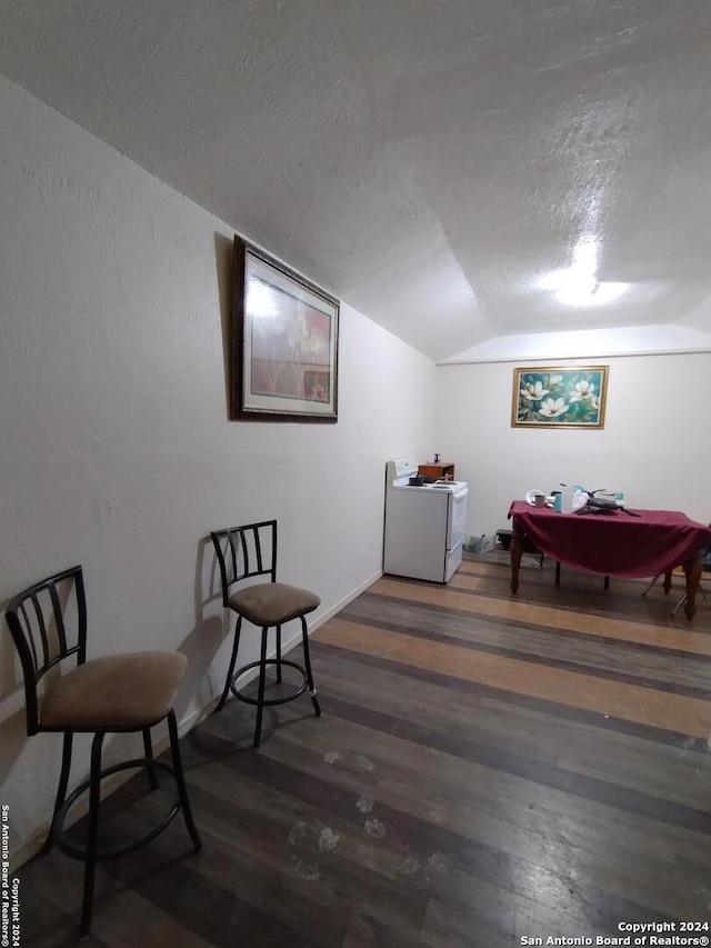 sitting room with a textured ceiling, washer / dryer, dark hardwood / wood-style floors, and lofted ceiling