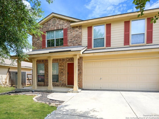 traditional-style home featuring covered porch, concrete driveway, a front yard, an attached garage, and brick siding