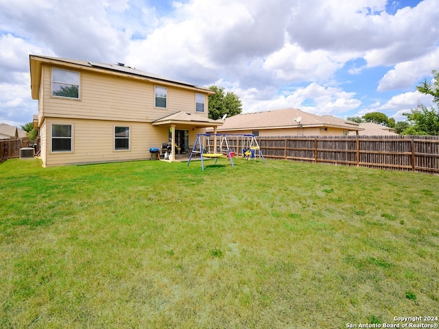 rear view of house with a lawn, a patio area, a playground, and central AC unit