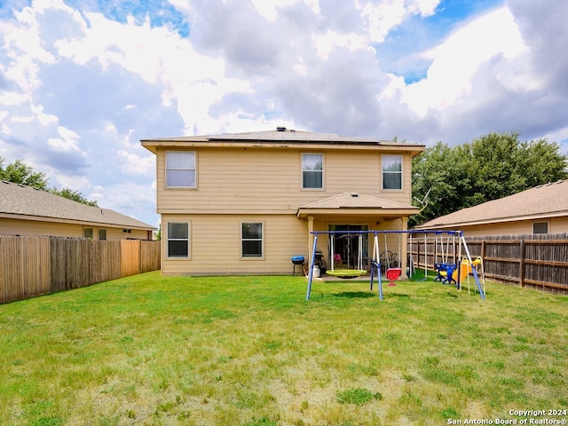 rear view of property with a playground and a lawn