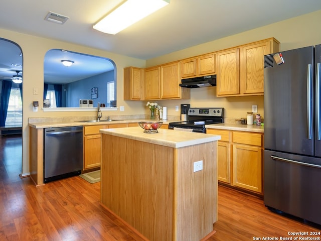 kitchen with a center island, hardwood / wood-style floors, appliances with stainless steel finishes, sink, and ceiling fan