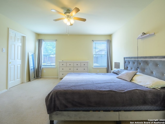 bedroom featuring multiple windows, ceiling fan, and light colored carpet