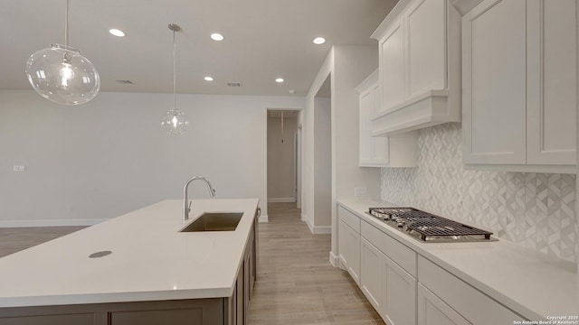 kitchen with a center island with sink, decorative light fixtures, and sink