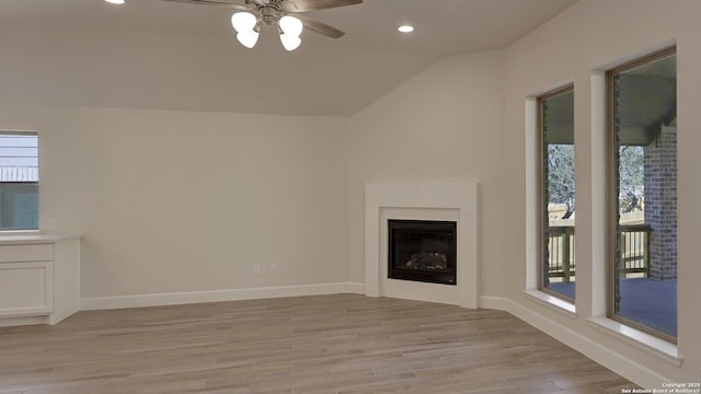 unfurnished living room featuring ceiling fan, light hardwood / wood-style flooring, a healthy amount of sunlight, and vaulted ceiling