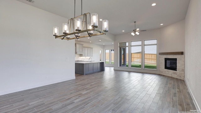 unfurnished living room with recessed lighting, a fireplace, wood finished floors, a ceiling fan, and baseboards